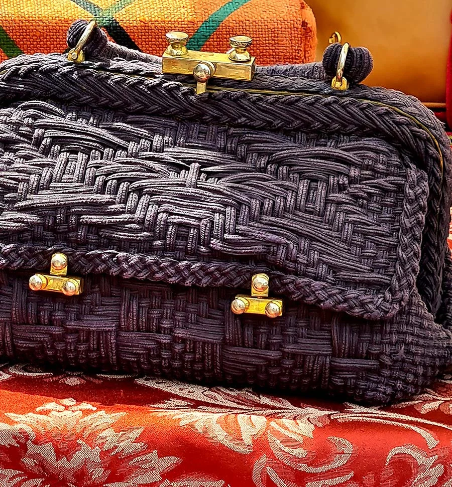 Roberta di Camerino vintage bag of dark woven cord with gold-tone clasps, resting on red damask