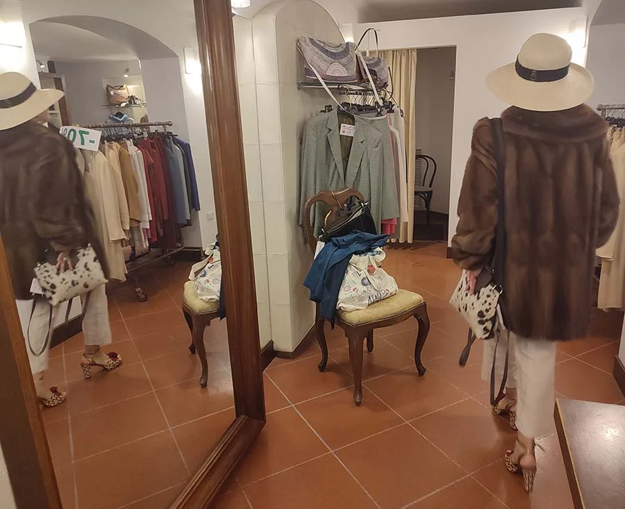 Back view of a vintage 1980s Fendi fur coat in brown with a cream hat, in a changing room with terracotta floor