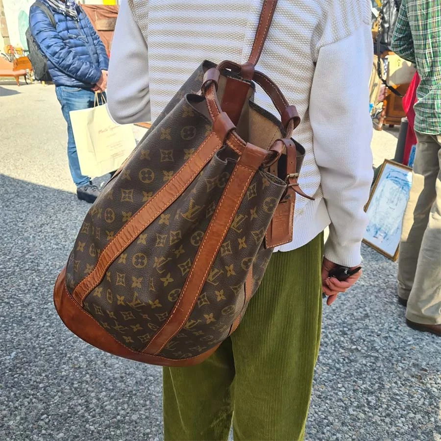 Vintage Louis Vuitton monogram bucket bag with tan leather trim, worn on the back with olive corduroy trousers