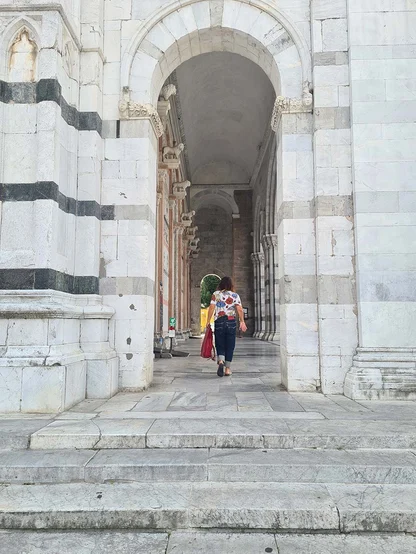 Gracie Opulanza in cuffed Levi's walking into a white marble archway, a red bag at her side