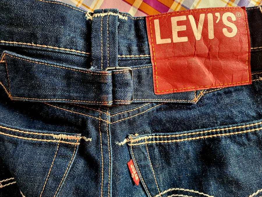 Red Levi's leather patch with white lettering on the waistband of dark blue vintage jeans