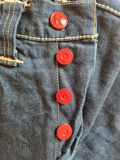 Row of red buttons down the fly of dark blue Levi's denim, with tan stitching