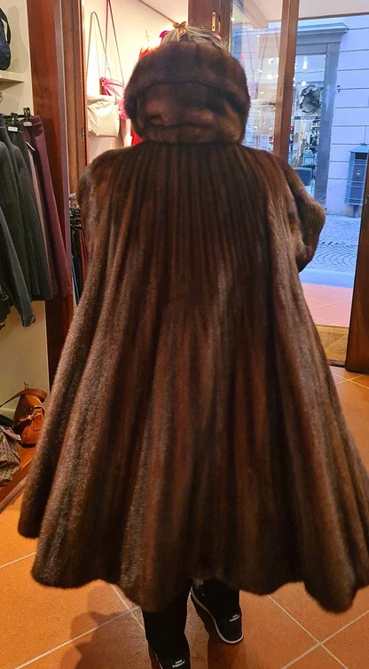 Back view of a long brown mink coat with a flared panelled skirt, in a shop