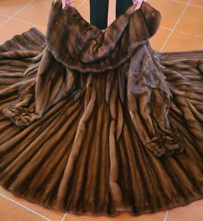 Brown mink coat held open on a tiled shop floor to show the full sweep of its panelled skirt