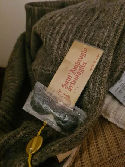 Sant'Ambrogio Made in Italy label and spare yarn on an olive green wool knit