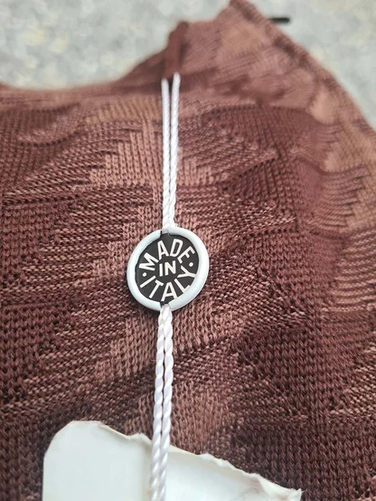 Brown patterned knit skirt with a round Made in Italy tag on a white twisted cord