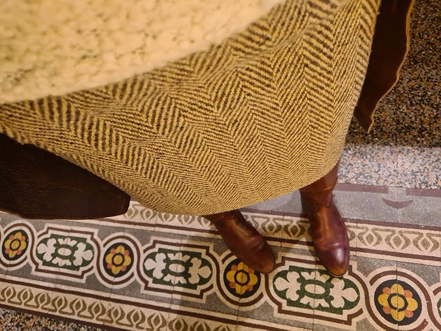 Brown and mustard herringbone wool skirt with brown leather ankle boots on a patterned mosaic tile floor