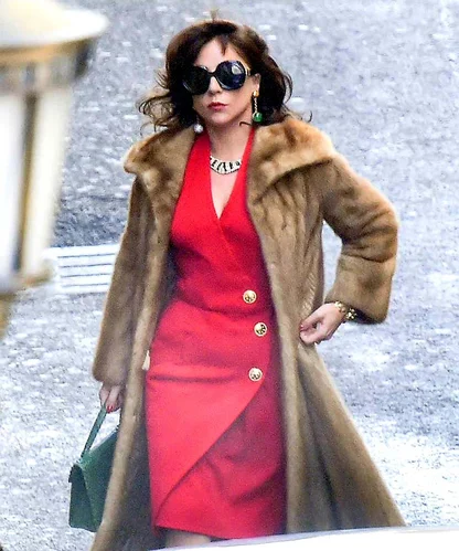 Lady Gaga in House of Gucci: a red double-breasted dress with gold buttons under a mink coat, carrying a green bag