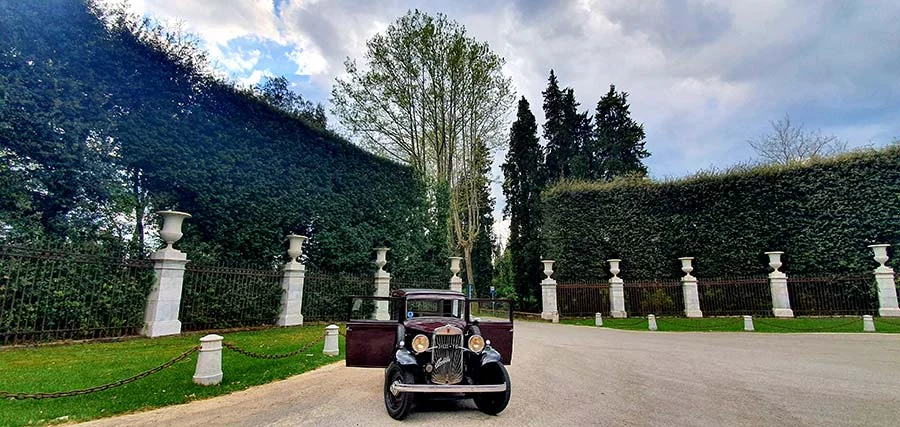 Black 1933 Fiat Balilla on a gravel drive between clipped hedges and stone urns at the Villa Reale