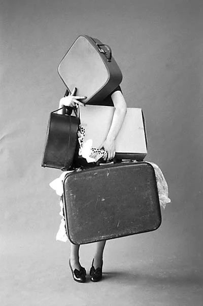 Black-and-white Tim Walker shot for Italian Vogue: Iris Palmer almost hidden behind an armful of suitcases