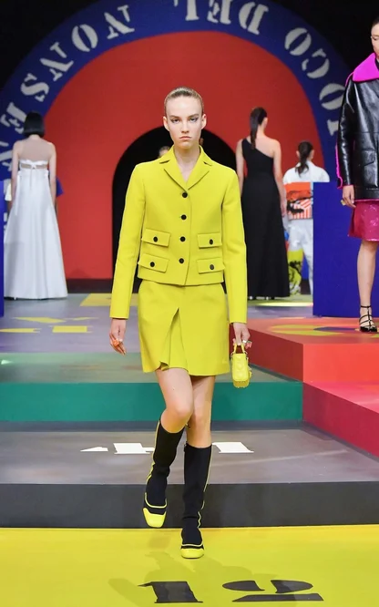 Runway look in chartreuse: boxy jacket with patch pockets, matching skirt, small yellow handbag and black boots