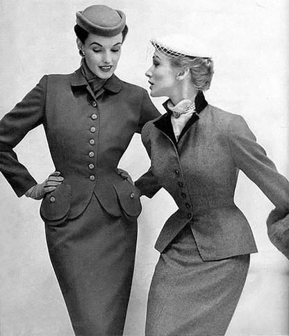 1950s black-and-white fashion photograph of two women in fitted tweed suits and small hats