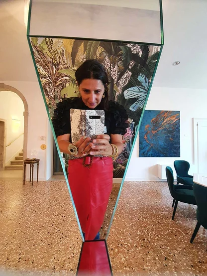 Gracie Opulanza photographing her reflection in an angled mirror, in a red leather skirt, in Venice