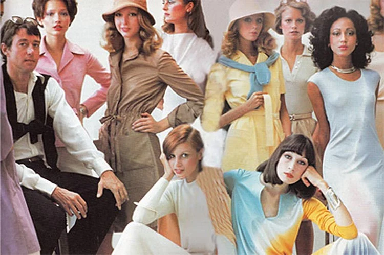 Group portrait of 1970s models in belted and draped dresses in tan, yellow, pale blue and pink, with a seated man at left