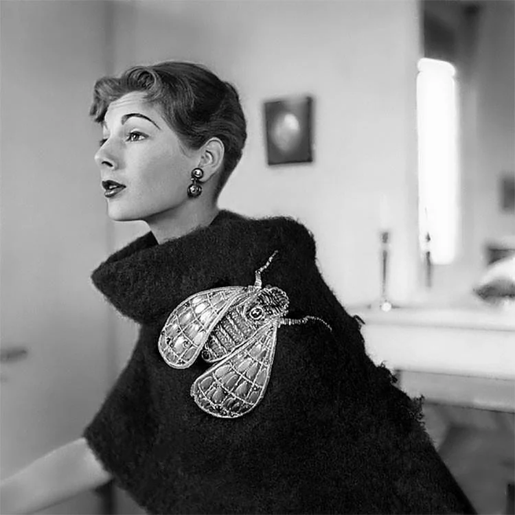 Black-and-white photograph of a woman in a black mohair top with a large silver insect brooch, a vintage Schiaparelli piece