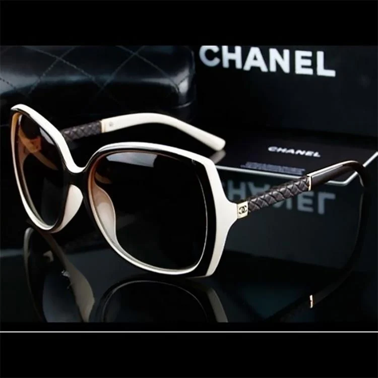 Chanel sunglasses with cream and black frames and quilted-leather arms, beside a Chanel box