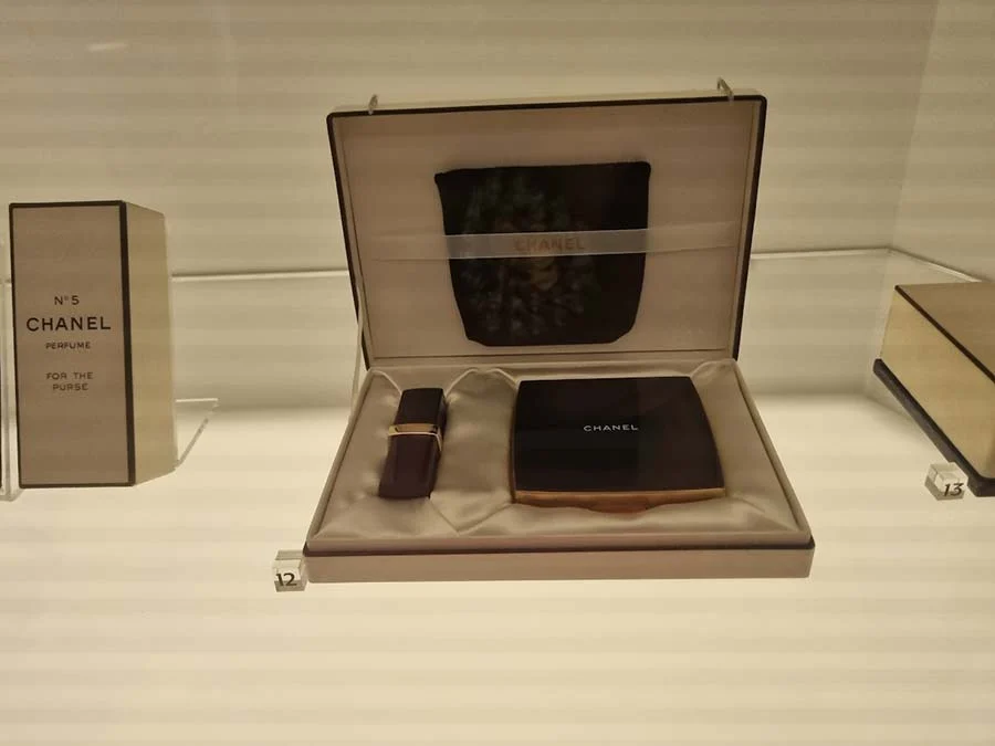 Chanel No 5 box and a boxed set holding a lipstick case and a compact, in a museum case