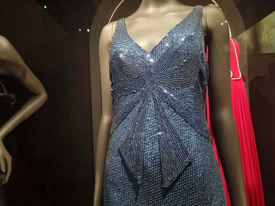 Blue sequinned and beaded evening dress with a bow motif across the bodice, on a mannequin