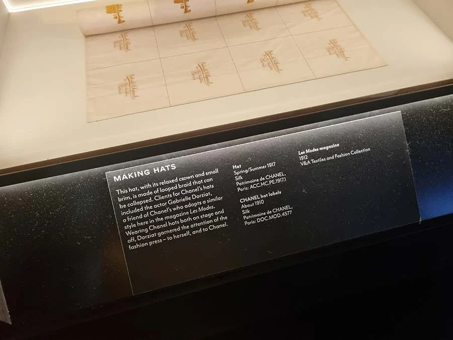 Museum label headed 'Making hats' beneath a sheet of Chanel hat labels