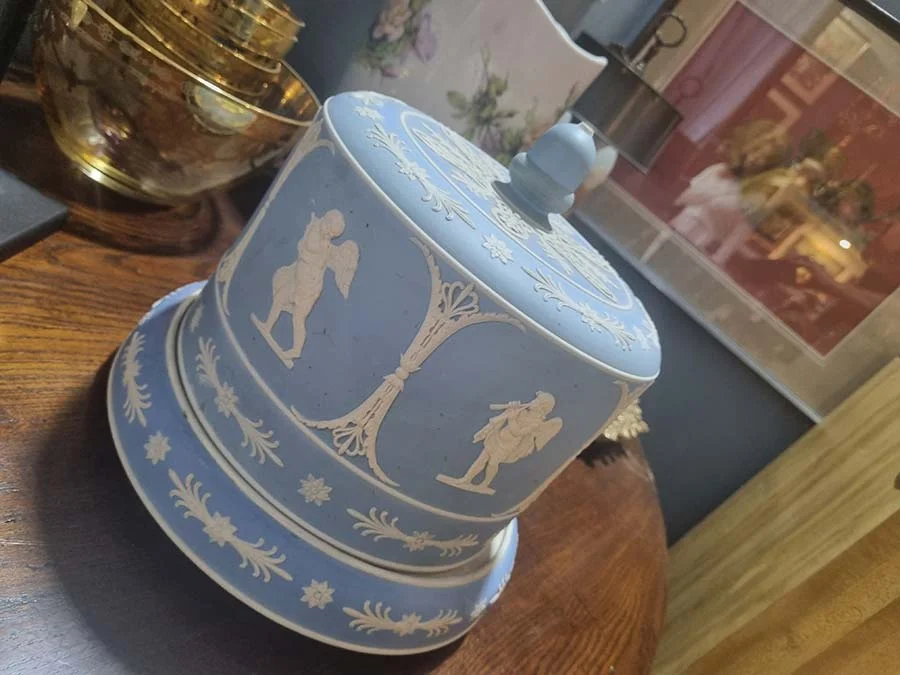 Blue and white cheese keeper with a domed lid and stepped base, standing on a wooden table