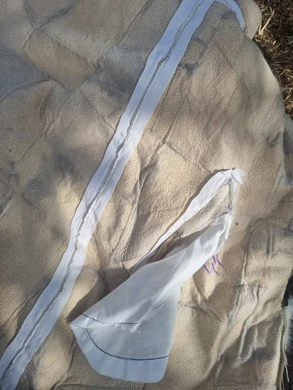 Pale pelt backing with a white tape seam and a loose triangle of white fabric, laid out on the ground