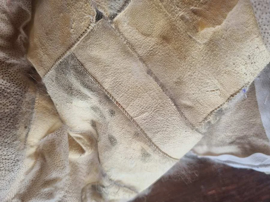 Close-up of cream leather pelt backing with pieces joined by fine stitched seams