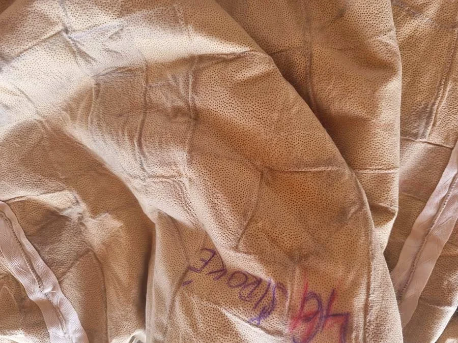 Beige pelt backing with purple pen marks and white seam tapes, creased where it lies