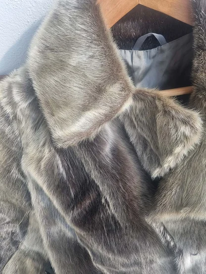 Wide fur collar of a seal fur coat on a wooden hanger, grey lining visible inside