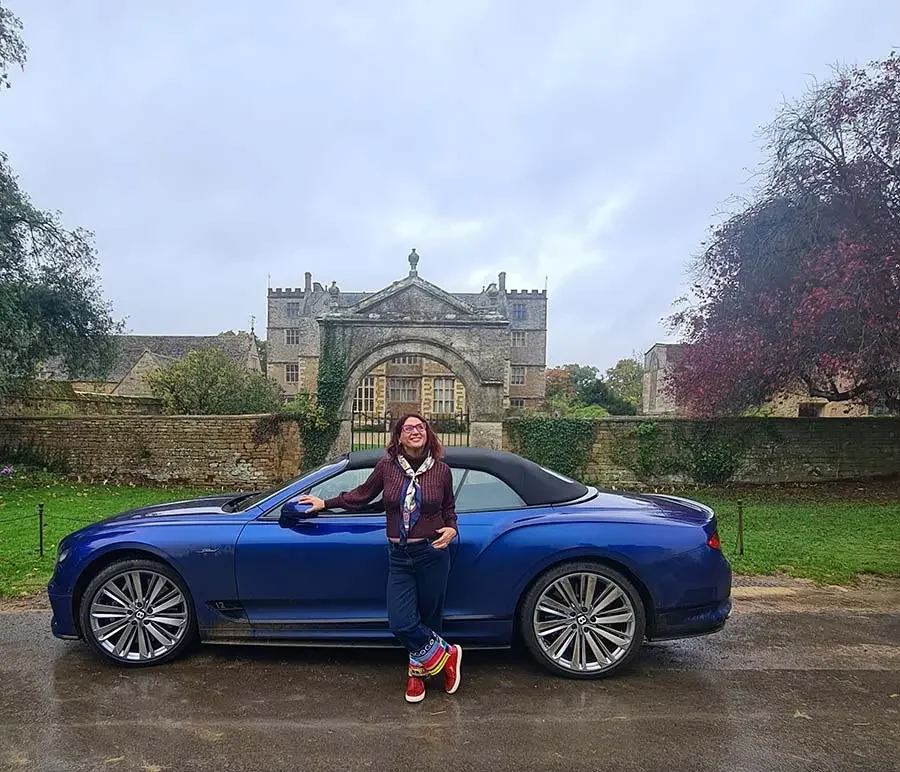 Gracie Opulanza beside a Moroccan blue Bentley GT Continental in the Cotswolds, wearing a printed Hermès scarf