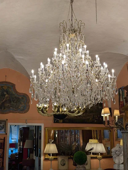 Tiered crystal chandelier with white bulbs, seen from below beneath a vaulted ceiling