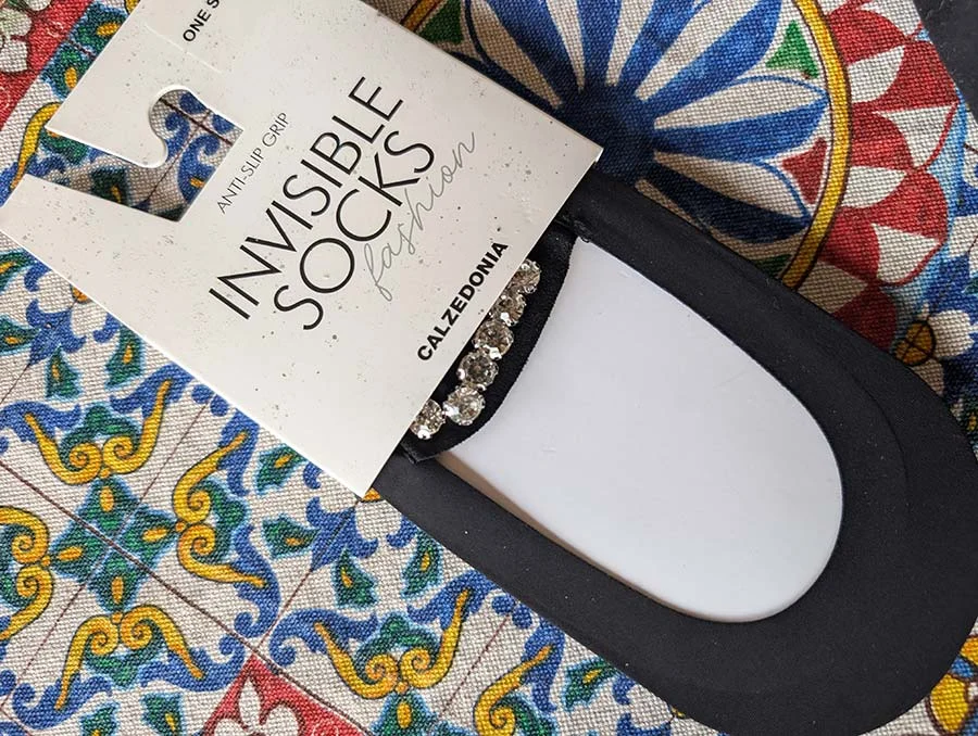 Calzedonia invisible socks with crystal trim in their packaging, on a blue, yellow and red tiled print cloth