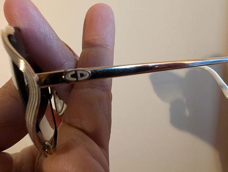 Dior CD logo on the metal arm of the 1980s sunglasses, held between finger and thumb