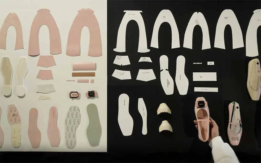 Ballet flat pattern pieces, soles and linings laid out on white and black, a hand holding a pink finished shoe