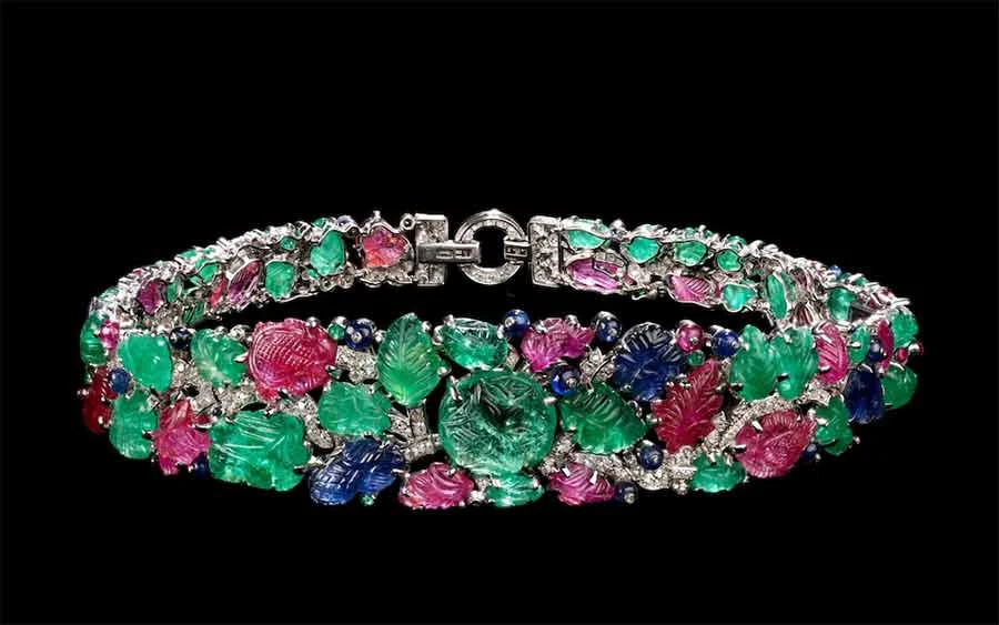 Tutti Frutti bandeau, 1928, of carved emerald, ruby and sapphire leaves set with diamonds, on a black background