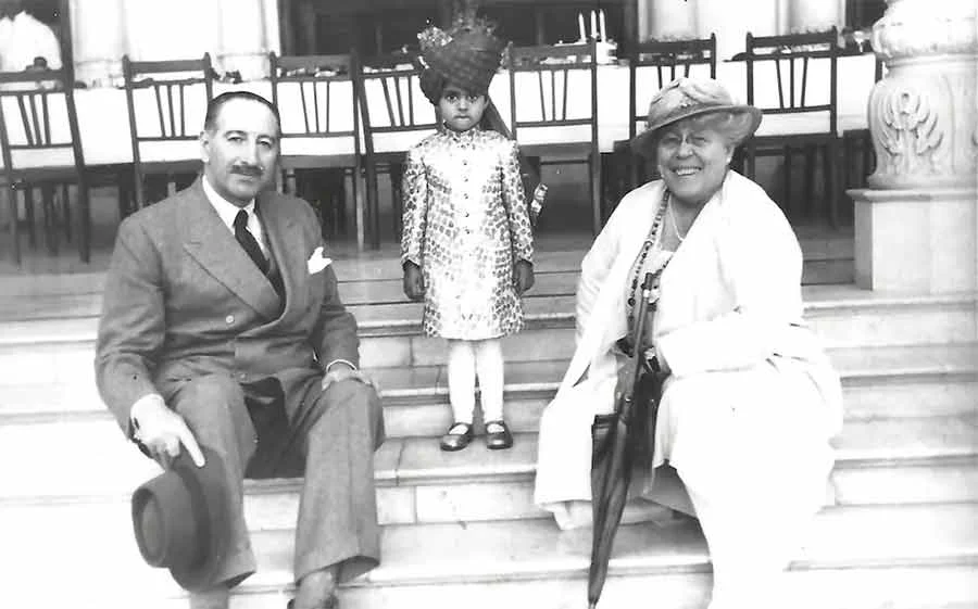 Black-and-white photograph of Jacques Cartier and his wife Nelly on steps in Nawanagar, India, with a Maharaja's child