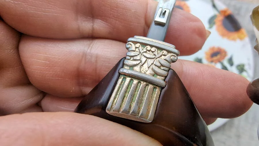 Close view of the silver-tone ornament, carved with a floral motif, on a dark tortoiseshell Gucci temple