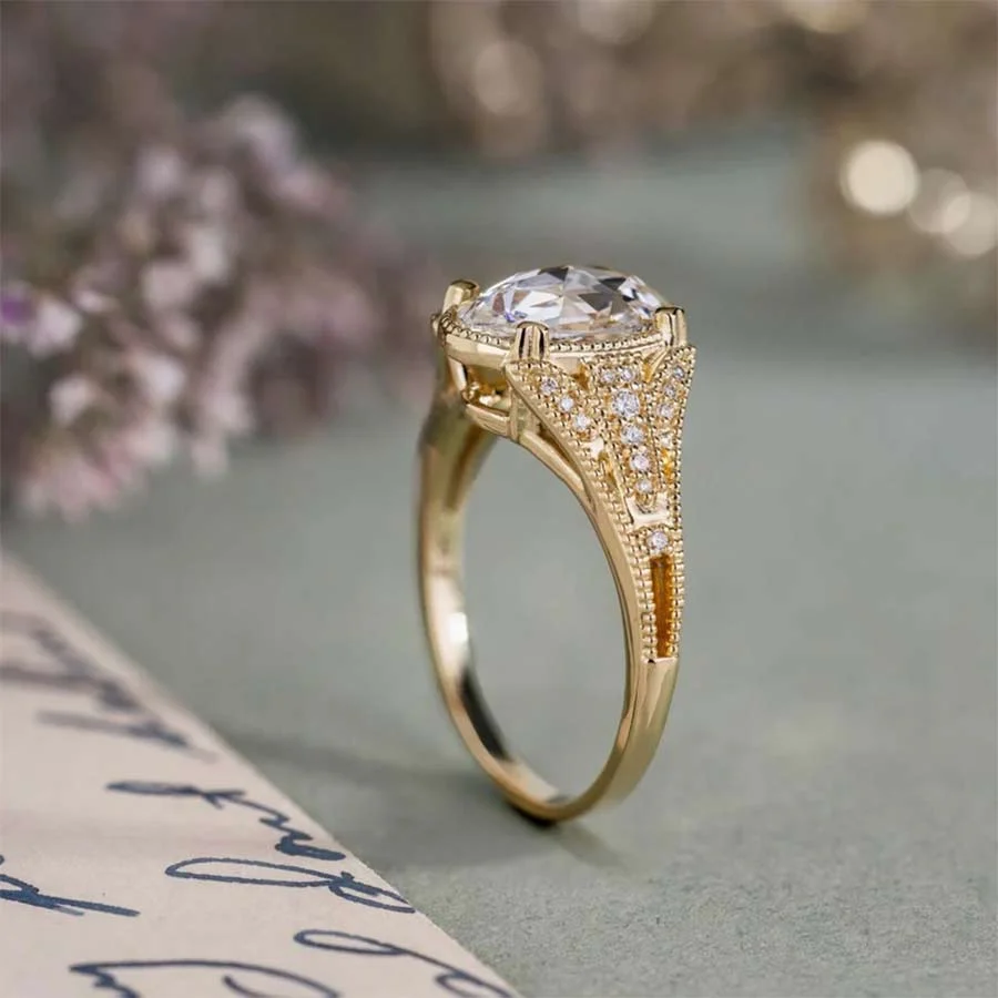 Yellow gold ring with a large central stone and diamond-set Art Deco style shoulders, beside a handwritten letter