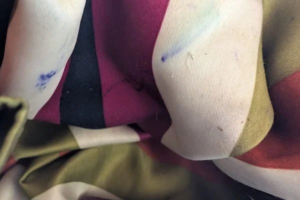 Striped bag lining in cream, plum and olive with small blue ink marks