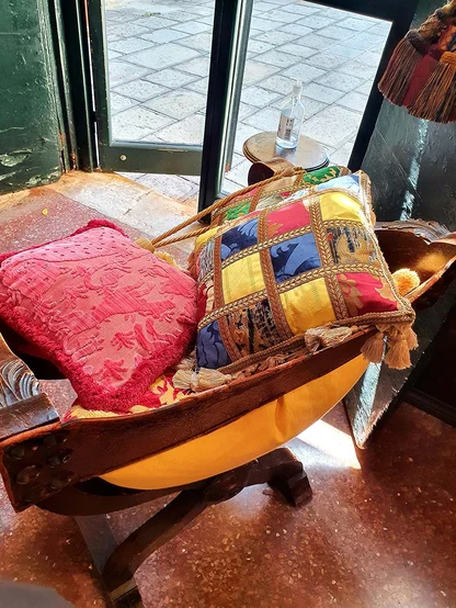 Patchwork velvet and damask cushions in red, blue and yellow on an old wooden folding chair