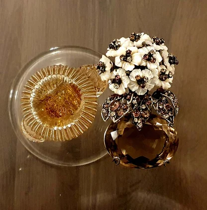The Iradj Moini brooch beside a small amber glass dish: white mother-of-pearl flowers over a faceted lemon quartz