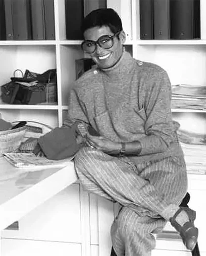 Smiling woman in large glasses, knit top and pinstripe trousers, Liz Claiborne design, 1980s black-and-white photo