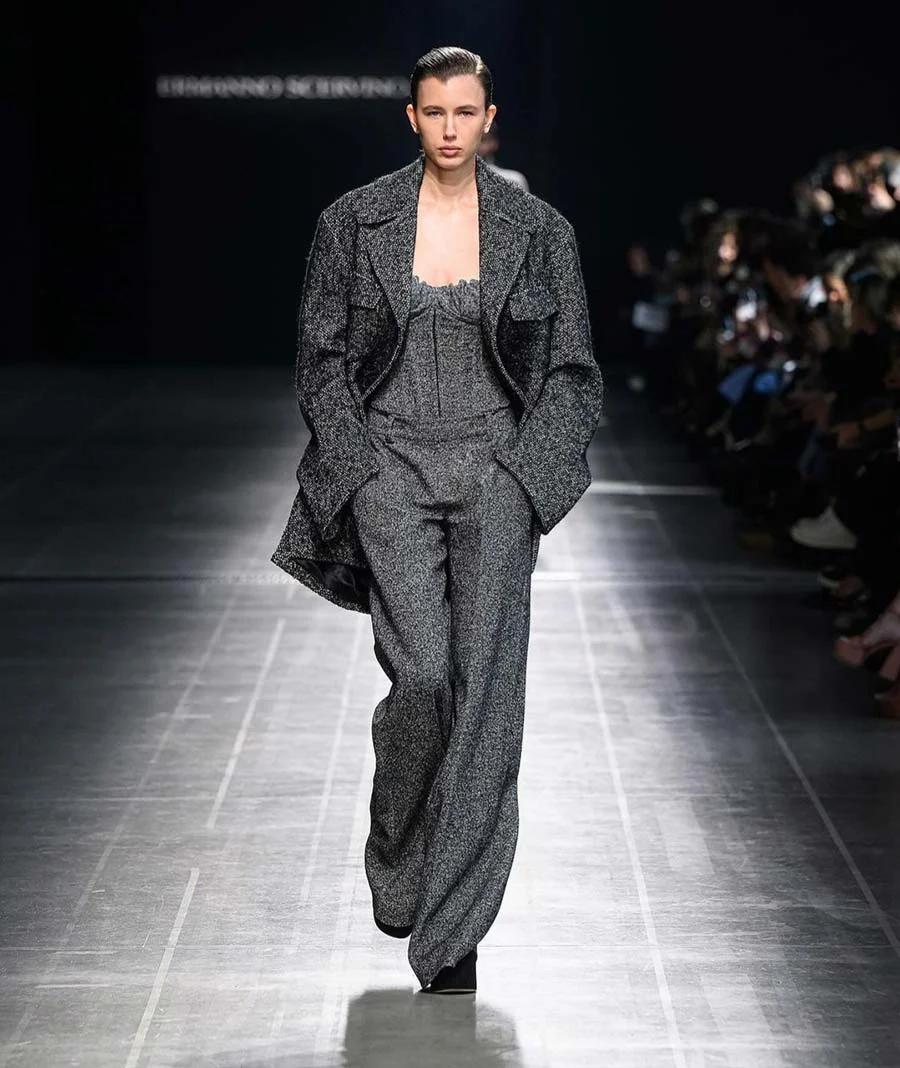 Grey tweed high-waisted trouser suit with a corset top and oversized jacket, on a runway
